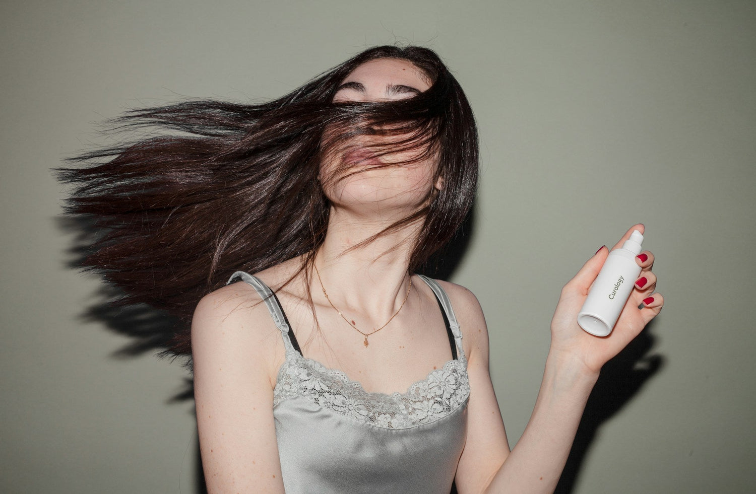 woman-spraying-hydrating-mist-on-her-face-while-looking-in-mirror